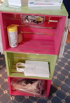 a pink, green and yellow shelf with papers on it's bottom shelf next to other items