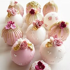 there are many pink and gold decorated chocolates in the shape of eggs with flowers on them