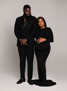 a man and woman in black clothes standing next to each other, posing for the camera