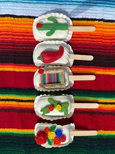 three plastic spoons are lined up in the shape of boats with flowers on them