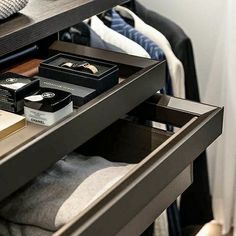 an open drawer in a closet with clothes and other items on the shelf next to it