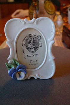 an ornate white frame with blue flowers on the edge is sitting on top of a table