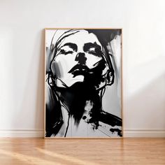 a black and white painting hanging on the wall next to a wooden floor in an empty room