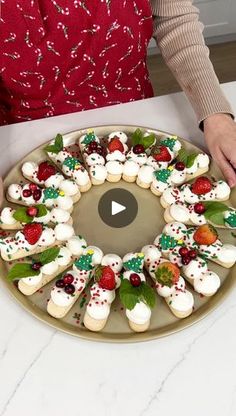 a woman is decorating a christmas wreath made of marshmallows and strawberries