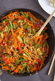 a skillet filled with vegetables and rice on top of a table