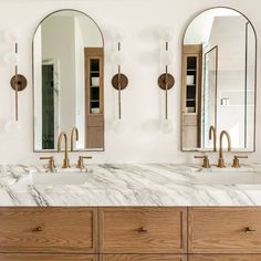 a bathroom with marble counter tops and two mirrors on the wall, along with gold faucets