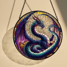 a stained glass dragon hanging from a chain on a light fixture with a circular window in the background