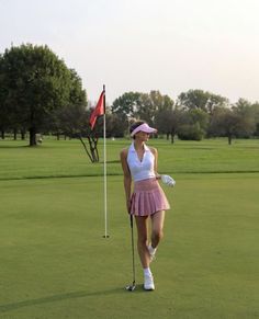 a woman standing on top of a green holding a white frisbee in her hand