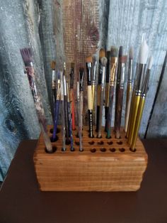 a wooden stand holding many different types of paintbrushes on it's sides