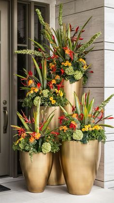 three large gold planters with flowers in them on the front step of a house