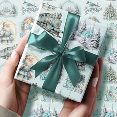 a woman's hand holding a wrapped gift box with a green bow on it