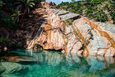 the water is crystal clear and blue in this pool at the bottom of a mountain