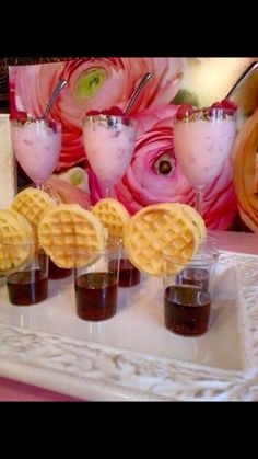 four waffles on a plate with drinks and flowers in the backgroud