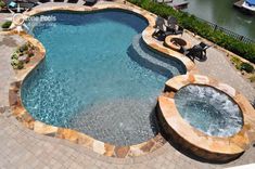 an outdoor swimming pool with hot tub and lounge chairs next to the side of it