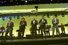 a group of men standing on top of a stage with musical instruments in front of them