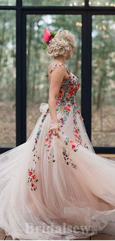 a woman in a flowered dress is standing on a wooden floor with her back to the camera