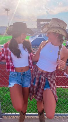 two young women standing next to each other wearing cowboy hats