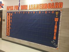 a bulletin board in the hallway of a school with orange and blue writing on it