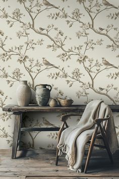 a table with a vase, potted plant and two birds on it next to a wallpaper