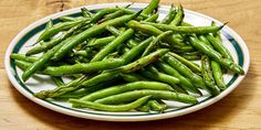 a white plate topped with green beans on top of a wooden table