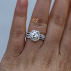 a woman's hand with a diamond ring on top of her wedding band and an engagement ring in the middle