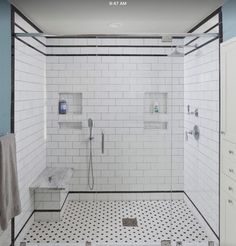 a white tiled shower with black and white floor tiles on the wall next to it