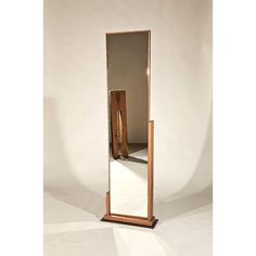 a tall wooden mirror sitting on top of a white floor next to a light brown wall