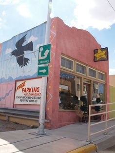 a parking sign in front of a pink building with a bird painted on it's side