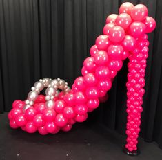 pink and silver balloons are arranged in the shape of a letter n on a black background