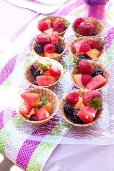 small bowls filled with fruit sitting on top of a purple and green tableclothed cloth