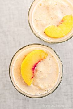 two glasses filled with smoothie topped with peach slices