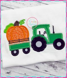 a green tractor with an orange pumpkin on the back is embroidered onto a white t - shirt