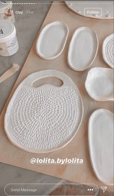 some white plates and spoons on a wooden table with paint in the back ground