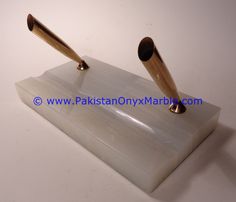 two pens sitting on top of a white marble block with gold tips and ends in the middle