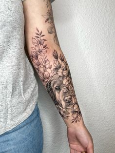 a woman's arm with flowers on it and a dog in the middle of her arm