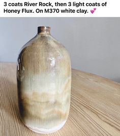 a brown and white vase sitting on top of a wooden table