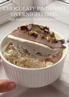 a person is holding a spoon over a bowl of ice cream with pistachio