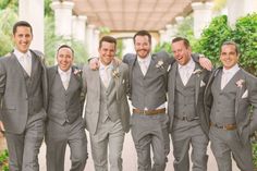 a group of men standing next to each other wearing grey suits and smiling at the camera