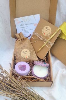 an open box containing candles, soaps and cards