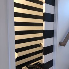 a black and white striped wall in a bathroom next to a stair case with a toilet