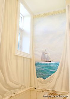 a painting on the wall of a bathroom with a sailboat in the water behind it