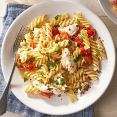 a white plate topped with pasta salad next to a bowl of chicken and tomato sauce