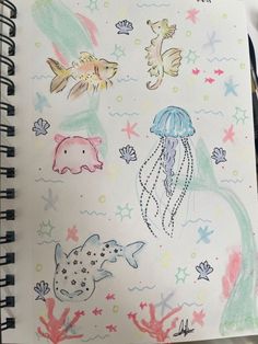 an open notebook with drawings of animals and jellyfishs on the cover, sitting on a table