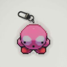 a pink and black keychain with an octopus on it's face in pixel art