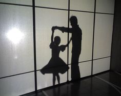 the shadow of a man and woman dancing in front of a wall with white panels