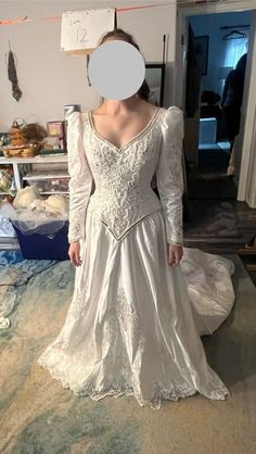 a woman in a white dress is standing on a bed with a paper circle over her face