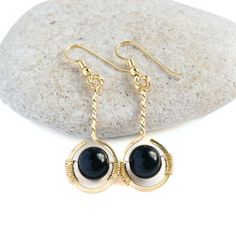 These earrings are so lovely! A black obsidian bead "floats" in an open circle frame of gold! Black obsidian is often associated with mystery and has a very strong ability to absorb. For this reason it is used often in feng shui, spiritual connection and protection. MATERIALGold filled wireGenuine black obsidian beadsSIZE8mm gemstones1.25 inch earring drop (excluding earring hooks)WHAT IS GOLD FILLED?We used to have just 2 choices: pure gold or gold plated. The first was very expensive, and the Gold Obsidian Jewelry As A Gift, Black Spiritual Earrings For Gift, Spiritual Black Earrings For Gift, Onyx Round Earrings For Gift, Round Onyx Earrings For Gift, Handmade Black Circular Jewelry, Round Obsidian Jewelry For Gift, Obsidian Round Jewelry For Gift, Obsidian Round Jewelry Gift