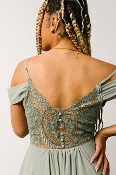 a woman with braids in her hair wearing an off the shoulder dress and looking down