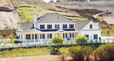 a large white house sitting on top of a lush green hillside