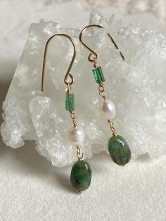 These long dangling earrings feature a combination of natural gemstones, including polished raw Emerald nuggets, Indicolite Tourmaline crystals, and creamy white freshwater Pearls. The Emerald nuggets showcase unique inclusions and natural matrix stone, while the Indicolite Tourmaline crystals have been polished just enough to soften the edges without losing their raw beauty.  The earrings are handcrafted with 14k gold-filled wire and ear hooks. With a total length of 5.3 cm, they are perfect bo Raw Emerald, Indicolite Tourmaline, Freshwater Pearl Earrings, Raw Beauty, Freshwater Pearls Earrings, White Freshwater Pearl, Tourmaline Crystal, Earrings Long, Dangling Earrings